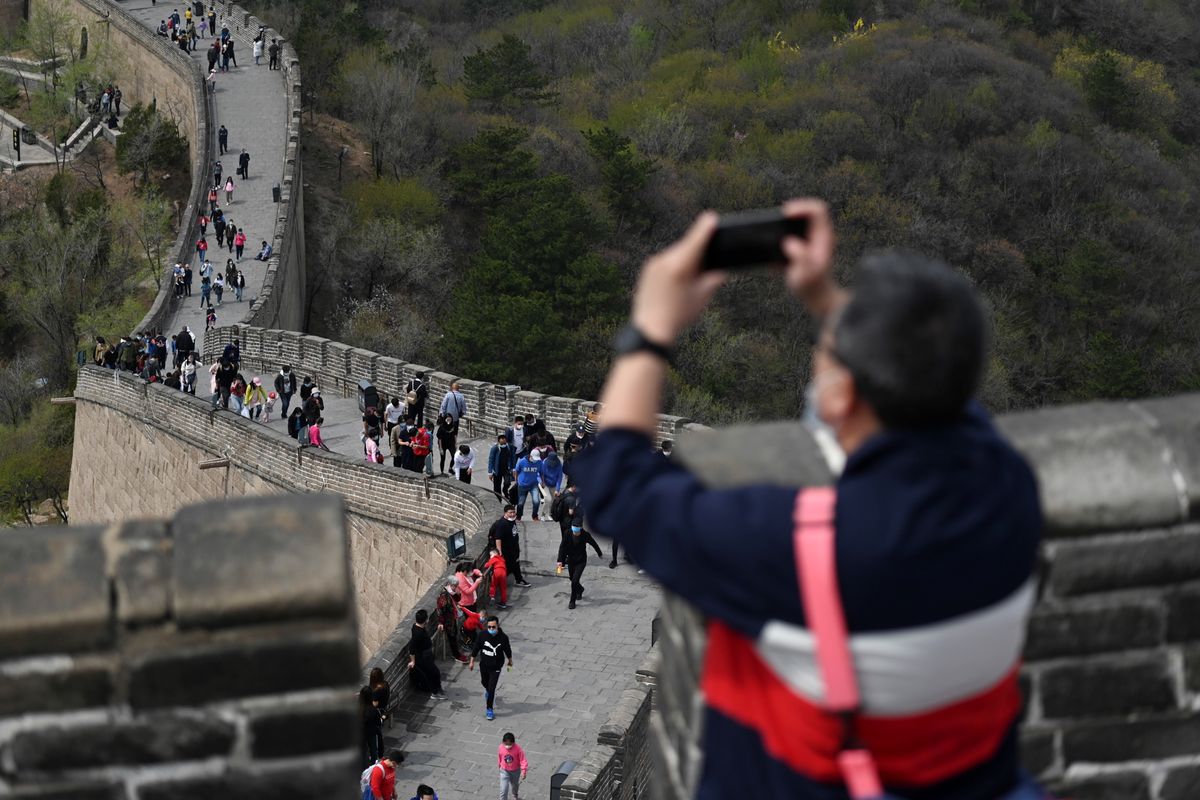 Pengunjung mengenakan masker untuk menghindari tertular Covid-19, saat mengunjungi Tembok Besar China, di Beijing, 18 April 2020. Setelah sempat menjalani masa karantina akibat penyebaran Covid-19, jutaan orang di China kembali turun ke jalan dan mengunjungi kawasan wisata yang kembali dibuka.