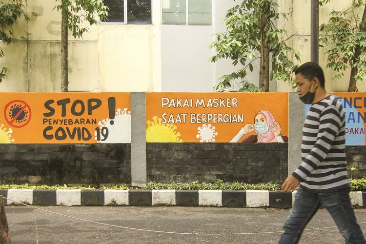 A passersby in Depok, West Java neglects to wear his mask as he walks past a Covid-19 themed mural urging the public to comply with health protocols urging their use on Wednesday, (6/1/2021).  ANTARA FOTO/Asprilla Dwi Adha/aww.