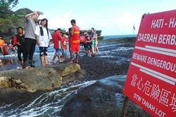 Wisatawan berfoto di area pantai di depan Pura Luhur Tanah Lot, Kabupaten Tabanan, Bali, Minggu (12/6/2016). 