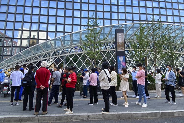 Orang-orang yang memakai masker wajah mengantre untuk tes COVID-19 di tempat pengujian selama hari kedua pengujian massal berturut-turut di Beijing, Rabu, 4 Mei 2022. 