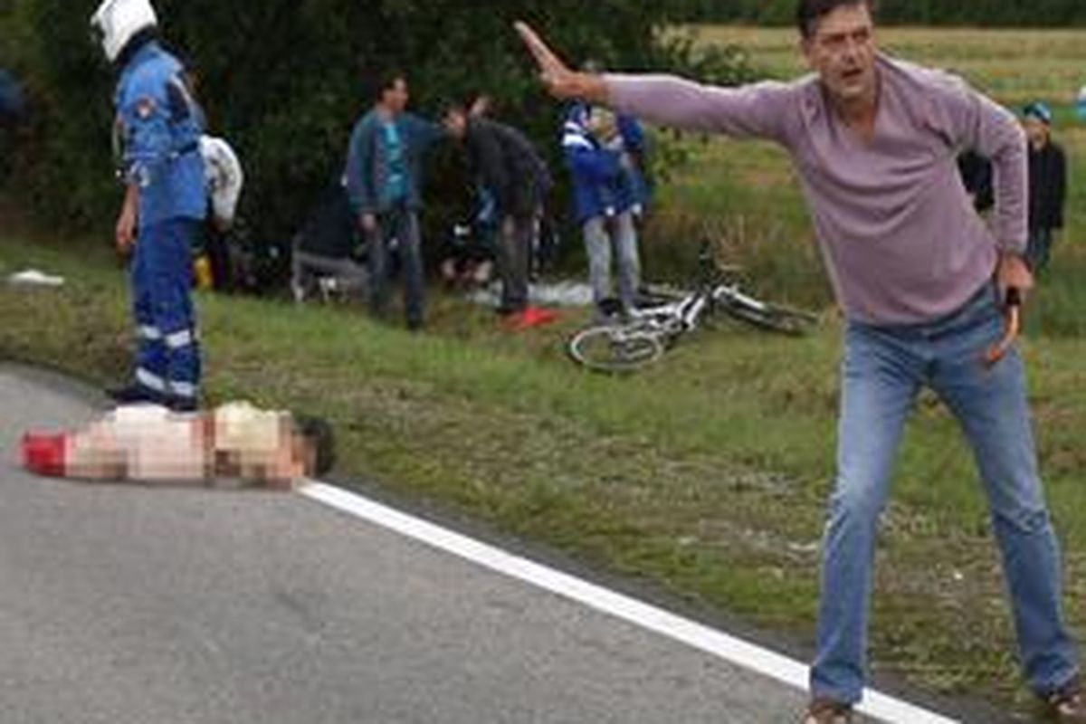 Seorang wanita tergeletak setelah tertabrak motor polisi. Wanita ini merupakan penonton Tour de France.