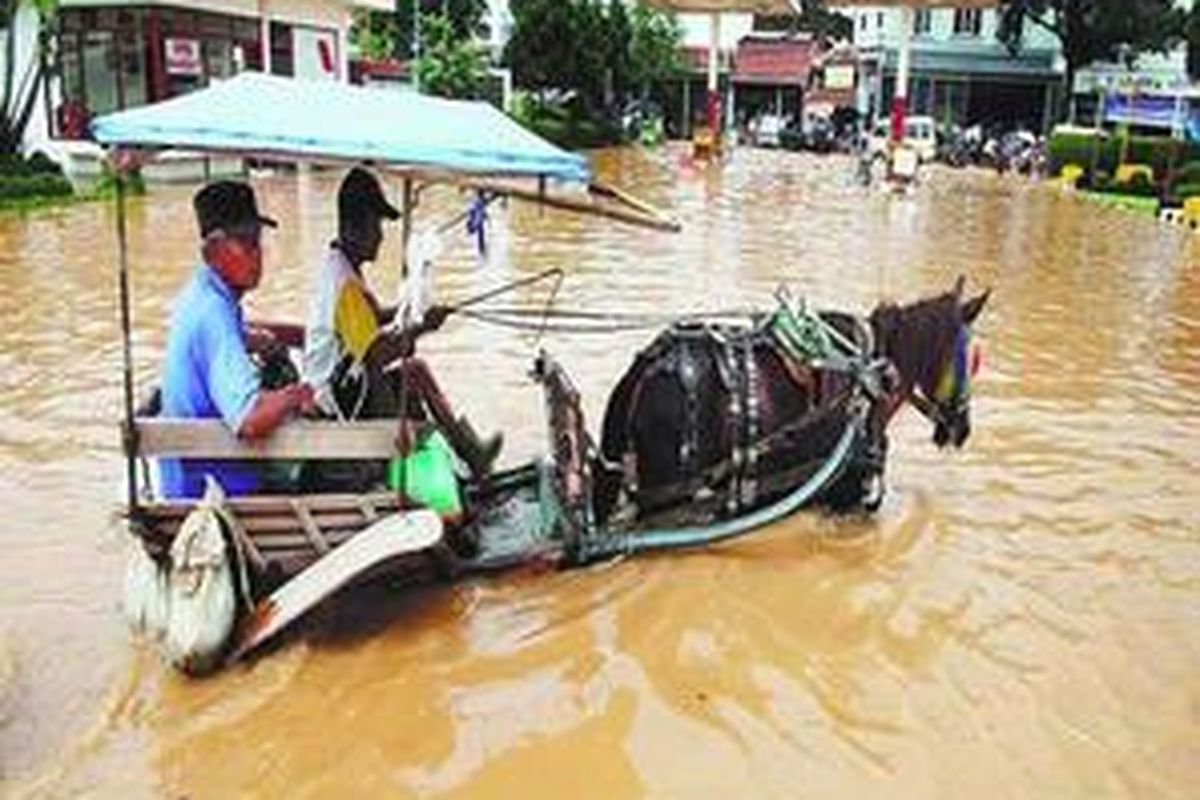  Banjir yang merendam permukiman warga di Kampung Cieunteung, Kelurahan Baleendah, Kabupaten Bandung, Jawa Barat, Kamis (4/12), semakin meluas ke jalan raya sehingga menyebabkan arus lalu lintas terputus. Warga terpaksa menggunakan jasa dokar dan perahu untuk menyeberang.