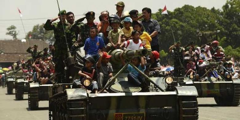 Warga mengikuti defile pasukan dengan menaiki tank saat peringatan HUT ke-67 Tentara Nasional Indonesia di lapangan Jenderal Soedirman, Ambarawa, Kabupaten Semarang, Jawa Tengah, Jumat (5/10/2012).  