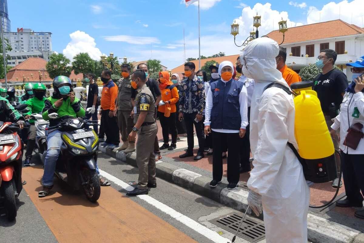 Gubernur Jatim Khofifah Indar Parawansa memantau penyemprotan disinfektan untuk pengendara ojek online di depan Gedung Negara Grahadi Surabaya, Minggu (22/3/2020).