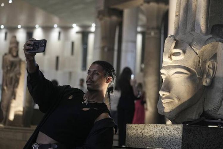 Seorang turis berswafoto di depan patung Arkhenaten di museum arkologi, Grand Egyptian Museum, Giza, Mesir pada Jumat (23/5/2025).
