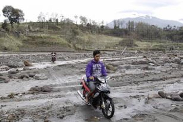 Warga berusaha melewati jalan yang terputus lahar hujan di Kali Pandansari, Desa Pandansari, Ngantang, Malang, Jawa Timur, 19 Februari 2014. Menurut BMKG, banjir lahar hujan ini mengalirkan 105 juta meter kubik material Gunung Kelud yang mengancam 28 desa di Kabupaten Blitar dan 6 desa di Kabupaten Kediri.