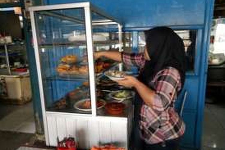 Fitri (35) yang merupakan pedagang warung nasi tegal di ruko Green Garden, Blok z, Jalan Panjang, Kedoya, Jakarta Barat. Terlihat sedang melayani pelanggannya pada Selasa(17/01/2017).