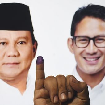 Warga menunjukkan jarinya yang telah dicelupkan tinta usai memberikan hak suaranya dengan latar poster Calon Presiden - Calon Wakil Presiden nomor urut 02 Prabowo Subianto - Sandiaga Uno di Surabaya, Jawa Timur, Rabu (17/4/2019). ANTARA FOTO/Zabur Karuru/wsj.