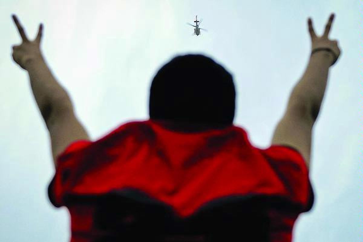 Demonstran anti- Pemerintah Bahrain mengacungkan tanda kemenangan pada helikopter militer yang terbang di atas Manama, Minggu (13/3). Polisi Bahrain bentrok dengan para demonstran yang berusaha menguasai pusat finansial Manama, menyusul meluasnya unjuk rasa ke wilayah bisnis di ibu kota Bahrain itu.