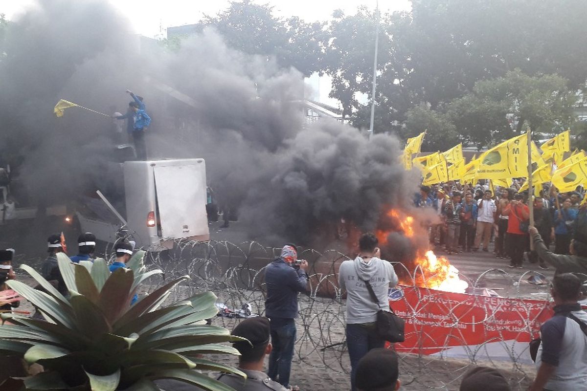 Asap hitam membumgung ketika massa mahasiswa dari PMII membakar ban dalam aksi unjuk rasa di depan Gedung Merah Putih KPK, Senin (23/9/2019).