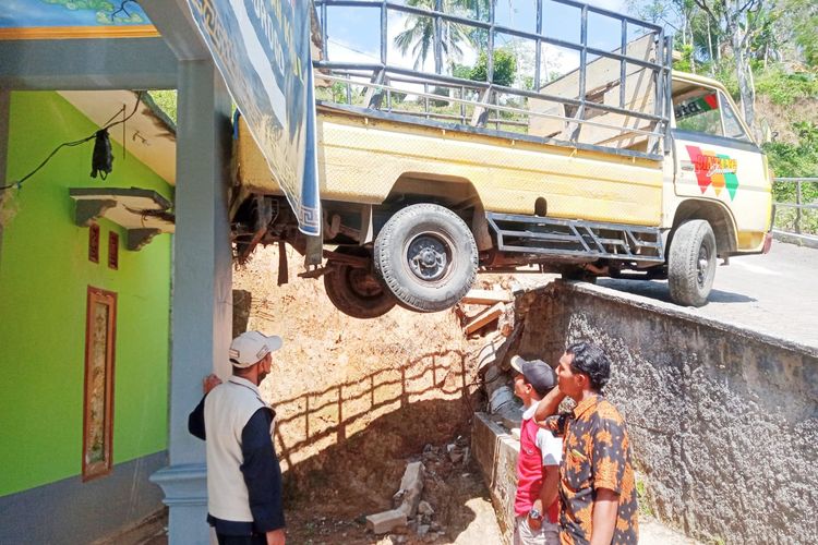 TIMPA ATAP—Sebuah mobil pick up yang mengangkut rombongan pengiring pengantin terperosok lantaran tak kuat menanjak hingga menimpa atap rumah warga di Desa Baosan Lor, Kecamatan Ngrayun, Kabupaten Ponorogo, Jawa Timur, Selasa (26/7) 2022)