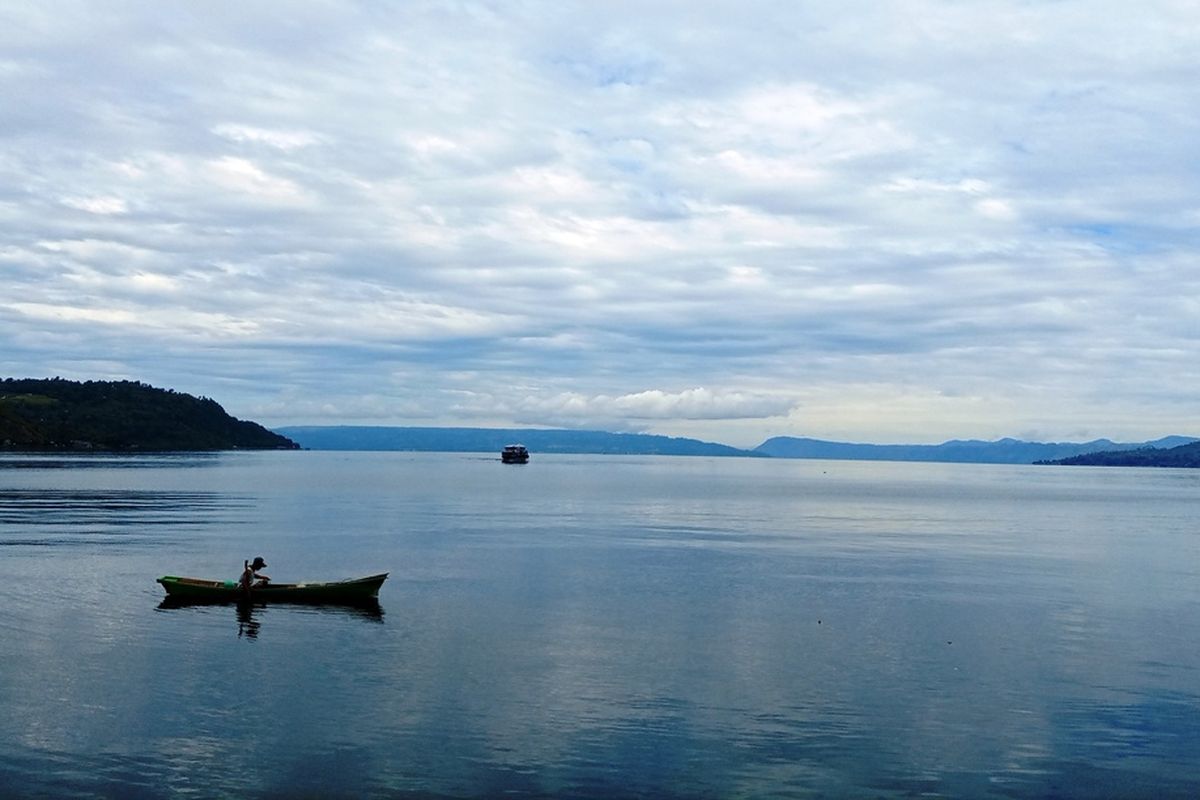 Danau Toba dengan Pulau Samosir dan nelayan pencari ikan, diambil dari salah satu sudut di Balige, Kabupaten Toba, Sumatera Utara