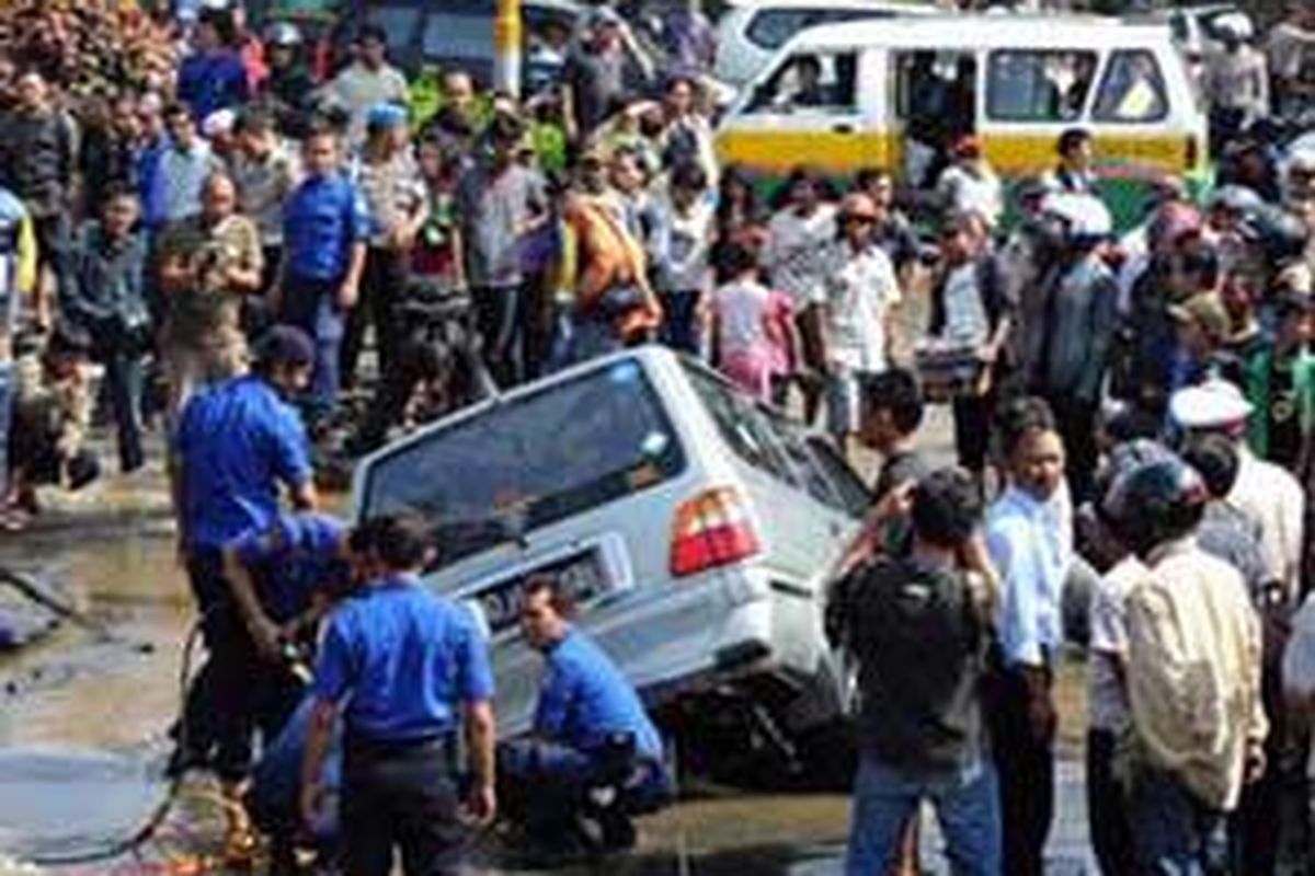 Petugas PDAM Kota Bandung berusaha menarik sebuah mobil kijang nopol D 1060 XB yang terperosok di badan jalan yang amblas akibat pecahnya pipa PDAM di perempatan Jalan RE Martadinata dan Jalan Ahmad Yani, Bandung, Rabu (24/12) siang.