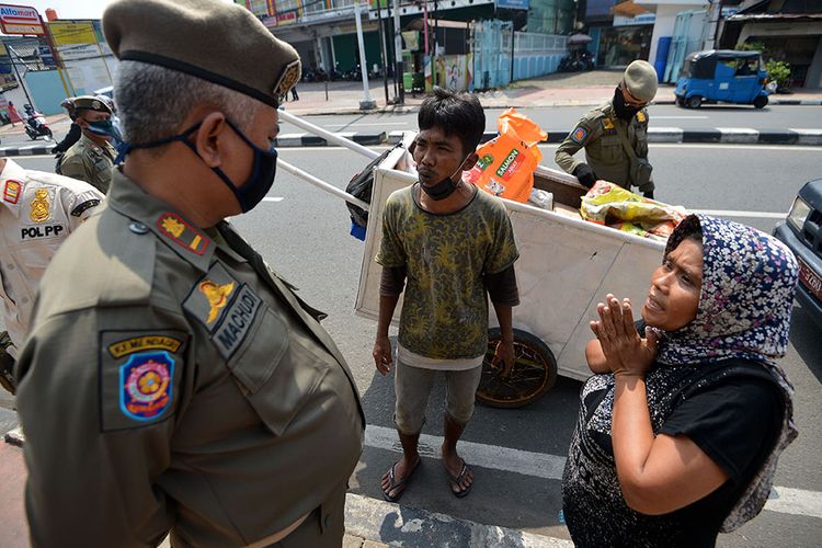 Petugas Satpol PP menginterogasi warga penyandang masalah kesejahteraan sosial (PMKS) di Jalan Dewi Sartika, Cawang, Jakarta, Rabu (29/4/2020). Pemerintah Provinsi DKI Jakarta menggalakkan penertiban PMKS yang berkeliaran saat penerapan pembatasan sosial berskala besar (PSBB) untuk mencegah penyebaran COVID-19.