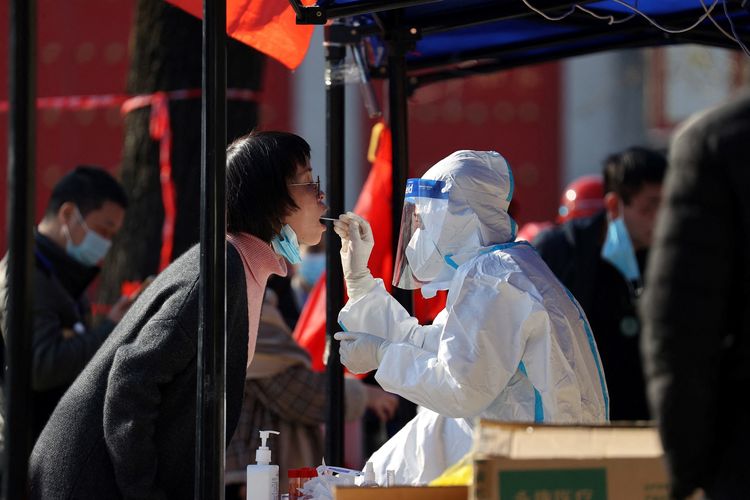 Seorang petugas medis melakukan tes swab kepada seorang warga di kota Xi'an, provinsi Shaanxi, China, Selasa (21/12/2021). Kota Xi'an di-lockdown mulai Rabu (22/12/2021) karena terjadi lonjakan kasus Covid-19.