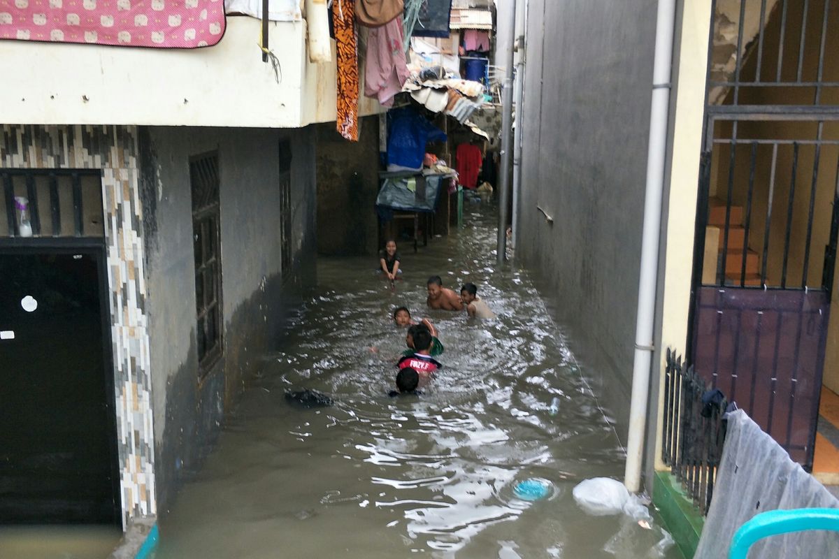 Anak-anak bermain air saat banjir merendam permukiman warga di RW 003 Kampung Pulo, Kelurahan Kampung Melayu, Jakarta Timur, Minggu (23/2/2020). 