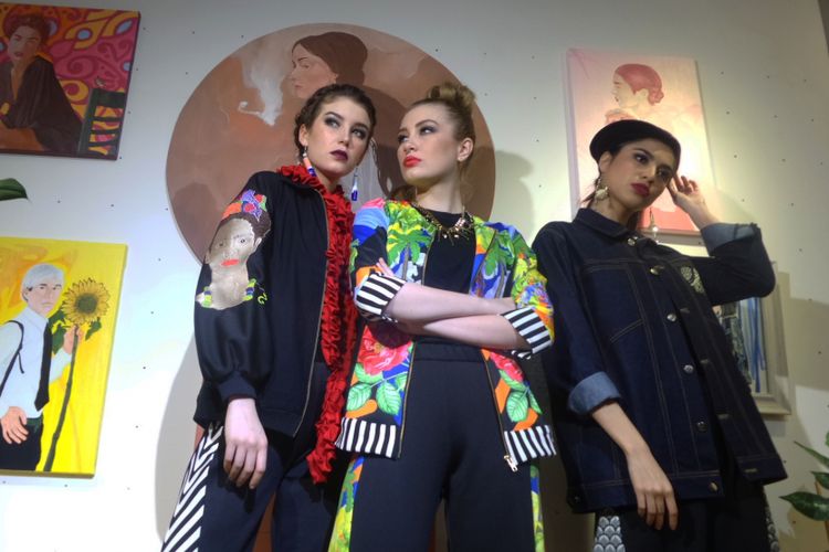 Tiga model mengenakan busana Avenue Apparel by 2madison dengan latar belakang karya seni dari seniman Bebe Wahyu.