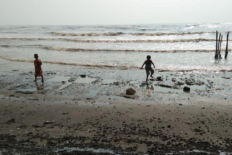 Anak-anak tengah bermain di dekat tumpahan minyak di pantai Desa Cemarajaya, Kecamatan Cibuaya, Kabupaten Karawang, Senin (22/7/2019).
