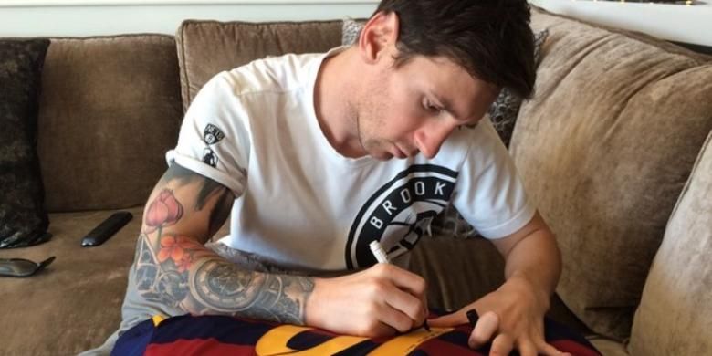 Lionel Messi menandatangani seragam Barcelona bernomor 10 untuk diberikan kepada Ronaldinho.
