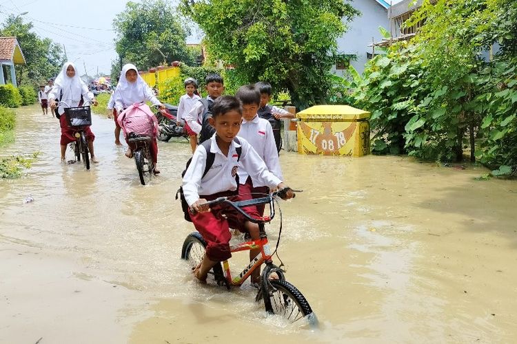Sejumlah anak-anak melintasi jalanan terendam akibat luapan Sungai Pemali yang mengakibatkan ratusan rumah di Dukuh Bayur, Desa Bojong, Kecamatan Jatibarang, Kabupaten Brebes, Jawa Tengah terendam banjir, Selasa (6/2/2024).