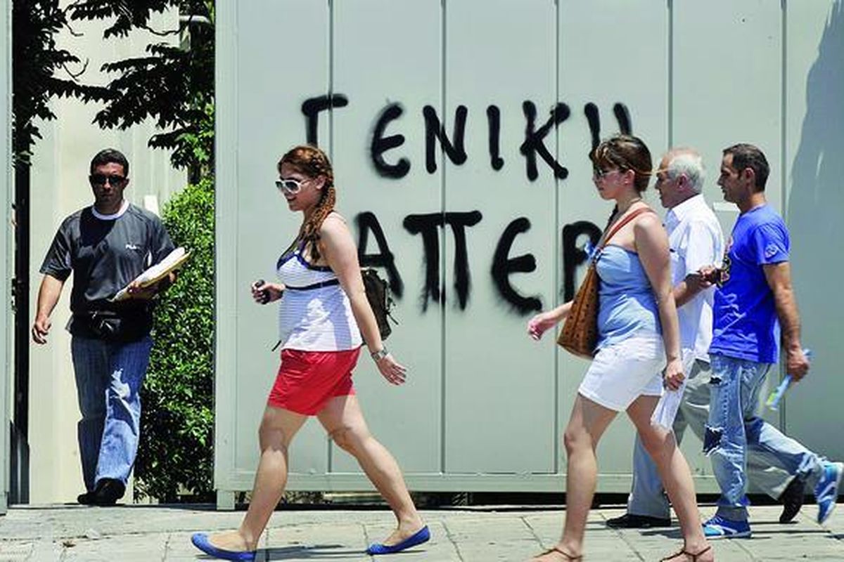 Wisatawan berjalan melewati dinding kantor pemerintah di Athena, Yunani, yang bertuliskan �mogok massal�, Selasa (21/6). Perdana Menteri Yunani George Papandreou menjamin program penghematan anggaran sebesar 28 miliar euro (Rp 346 triliun) berjalan sesuai rencana menjelang pemungutan suara mosi tidak percaya, 21 Juni. Jaminan ini dinilai sebagai kunci untuk meredakan kekhawatiran tentang masa depan euro.