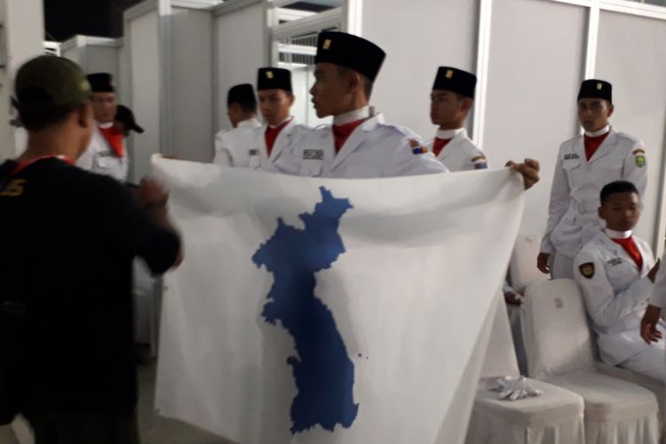 Seorang Paskibra bersiap mengibarkan bendera Korea Bersatu yang dipinjam jelang penyerahan medali di salah satu nomor cabang para renang Asian Para Games di Stadion Akuatik, Senayan, Jakarta, Senin (8/10/2018) malam. Penyerahan medali akhirnya batal dilakukan.