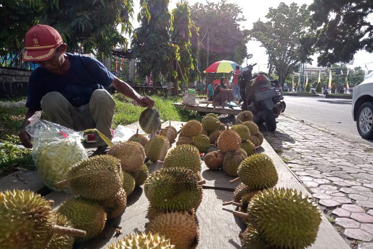 Babe Hadi saat menata dagangan buah durian di trotoar jalan pahlawan Manokwari 