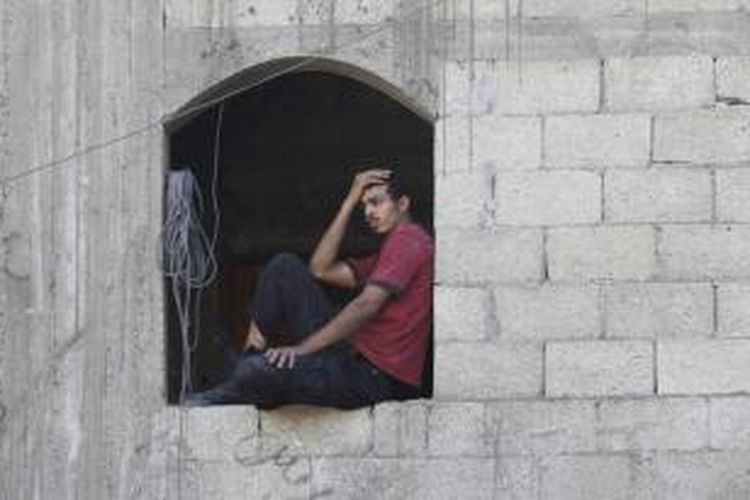 Seorang pria Palestina melihat tim penyelamat mencari korban di sebuah rumah yang hancur akibat serangan udara Israel di kota Khan Yunis, jalur Gaza, 8 Juli 2014. Serangan tersebut menewaskan puluhan warga Palestina termasuk wanita dan anak-anak.