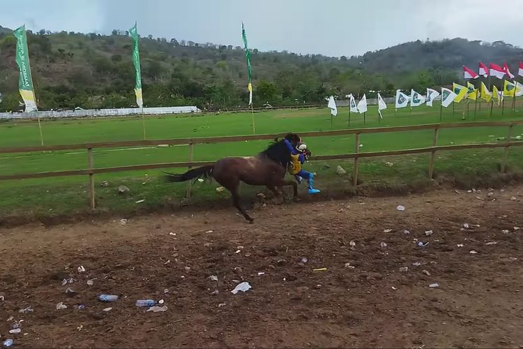 Tampak joki anak bergelantungan di leher kuda bernama James Bond di arena pacuan Panda, Kabupaten Bima, Rabu (12/10/2022).