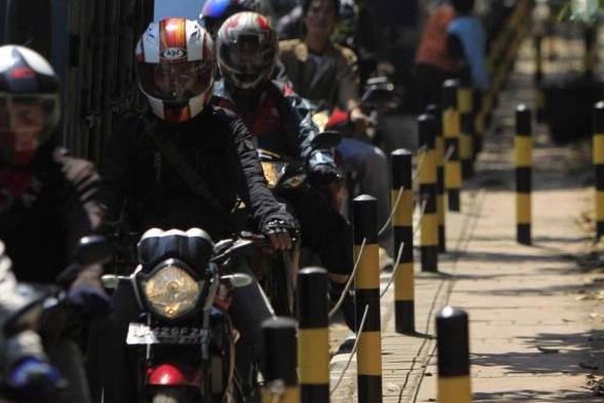 Pengguna sepeda motor tersendat di samping trotoar yang dipasangi tiang besi dan kawat baja di Jalan Raya Bekasi, Cakung, Jakarta Timur, Senin (16/4/2012). Tiang besi dan kawat baja dipasang untuk menutup jalan ke trotoar yang sering dipakai pengguna sepeda motor saat macet.