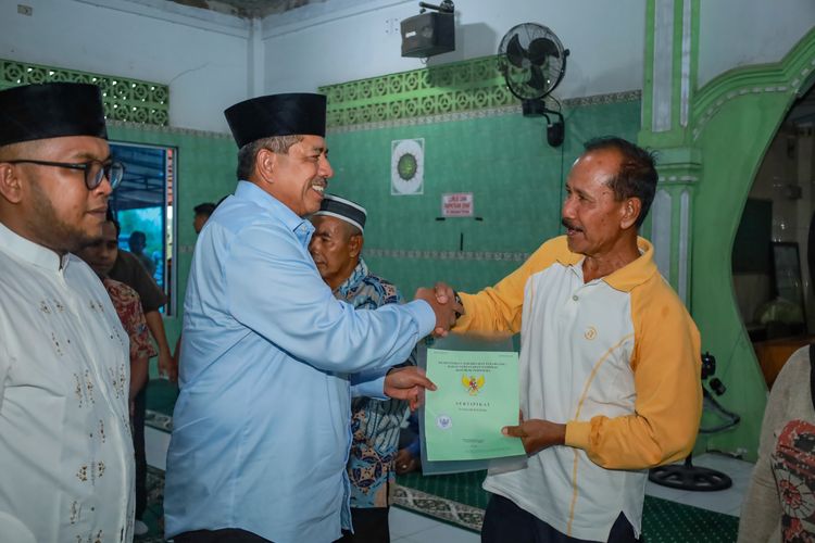 Bupati Siak Alfedri saat menyerahkan sertifikat tanah kepada salah satu warga Minas Jaya.