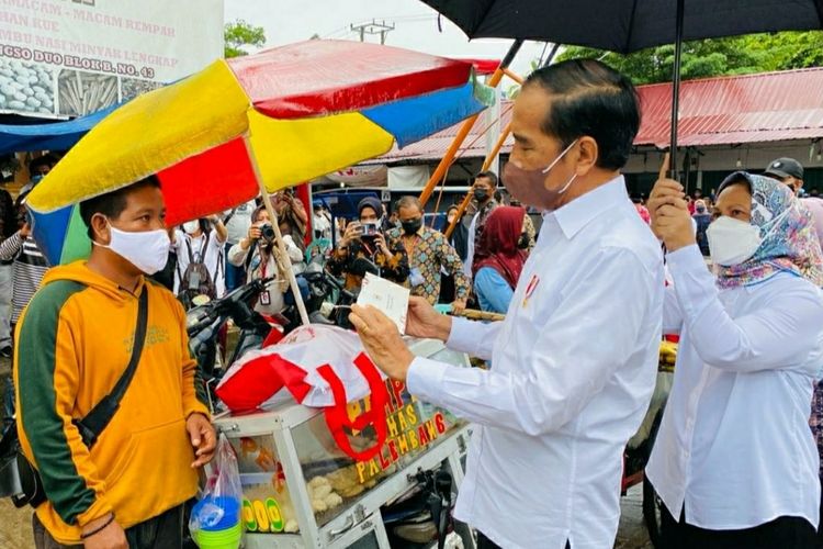 Presiden Joko Widodo bersama Ibu Negara Iriana Jokowi saat memberikan Bantuan Langsung Tunai (BLT) minyak goreng kepada sejumlah pedagang kecil dan penerima di Pasar Rakyat Angso Duo Baru, Kota Jambi, Kamis (7/4/2022).