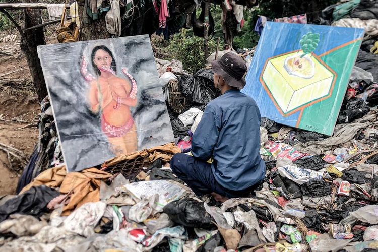 Seorang pengunjung tengah melihat karya lukis yang di pamerkan di gunungan sampah TPA Sarimukti, Bandung Barat, Jawa Barat, Kamis (28/12/2023).