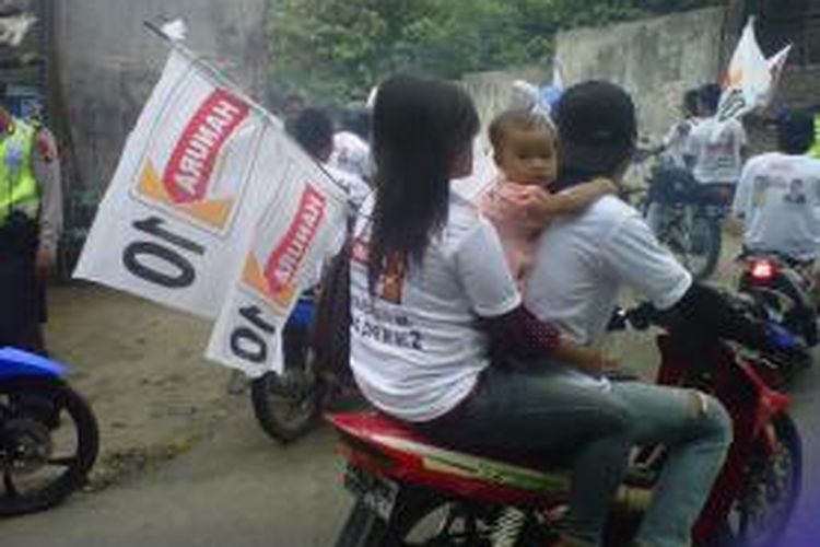 Salah seorang anak balita terlihat dibonceng kedua orangtuanya ikut konvoi kampanye partai Hanura di Desa Borobudur, Kecamatan Borobudur, Kabupaten Magelang, Jumat (21/3/2014).