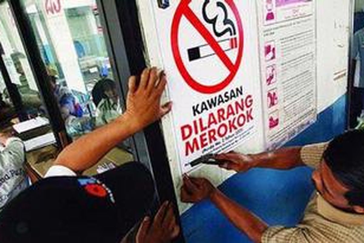 Ilustrasi: Petugas memasang poster Kawasan Dilarang Merokok.