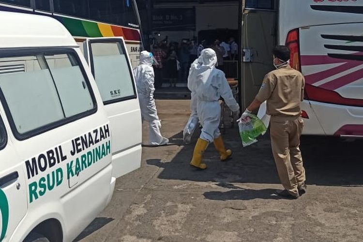 Petugas berpakaian hazmat mengevakuasi seorang penumpang yang ditemukan meninggal di dalam bus di Terminal Bus Kota Tegal, Jawa Tengah, Senin (27/7/2020). (Dok: Polsek Sumurpanggang, Polres Tegal Kota)