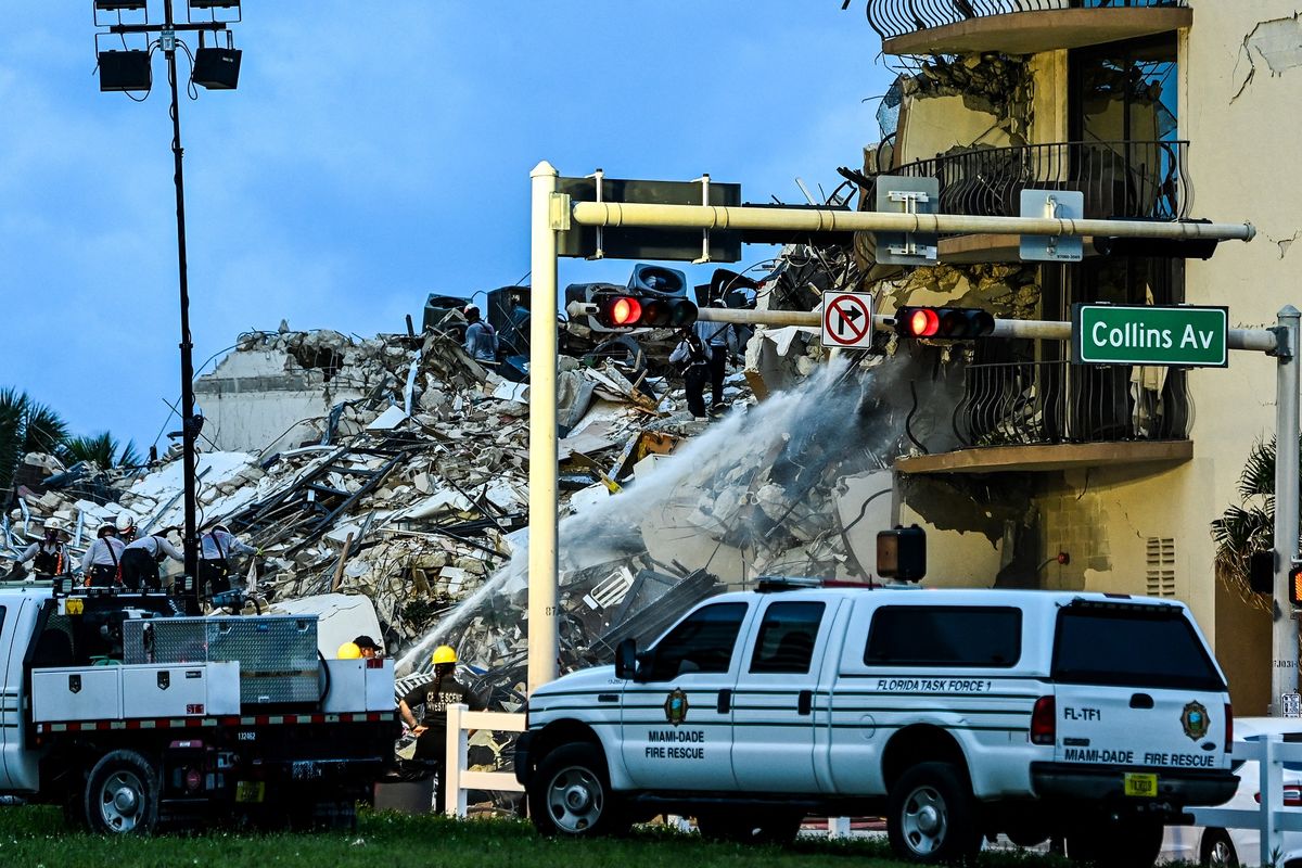 Tim SAR bersama pemadam kebakaran Miami Dade melakukan operasi pencarian di apartemen yang ambruk sebagian di Surfside, Miami, Florida, Amerika Serikat, pada Kamis (24/6/2021). Hingga Jumat pagi (25/6/2021) dilaporkan satu orang tewas dan 99 korban hilang.