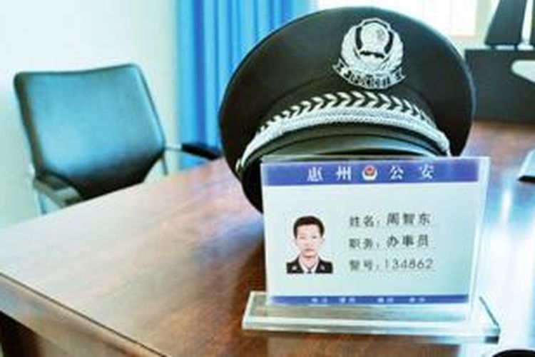 Topi kerja dan foto petugas polisi Zhou Zhidong (45) ditaruh di meja kerjanya di pos polisi Huangbu untuk mengenang pria yang tewas setelah bekerja 24 jam penuh.