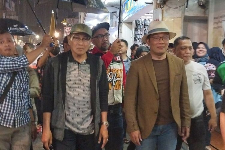 Gubernur Jawa Barat Ridwan Kamil bersama Wali Kota Tasikmalaya Muhammad Yusuf berjalan kaki menyusuri Jalan HZ Mustofa sebagai kawasan Maliboro-nya Tasikmalaya sembari hujan-hujanan dan diteriaki Calon Presiden 2024, Sabtu (8/10/2022).