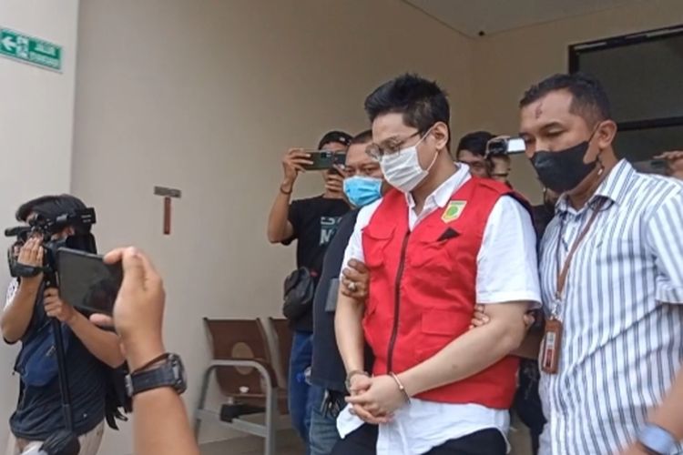 Tersangka kasus afiliator Binomo Indra Kenz menggunakan rompi tahanan Kejari Tangsel saat akan dibawa menggunakan mobil tahanan ke Rutan Mabes Pori, Jumat (24/6/2022). Indra Kenz akan ditahan selama 20 hari di Rutan Mabes Polri.