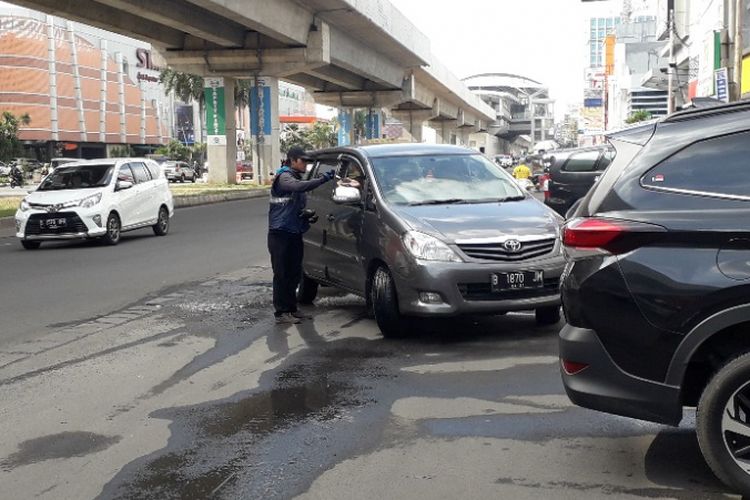 Seorang juru parkir bertransaksi dengan pengendara di kawasan Kelapa Gading, Kamis (17/1/2019).