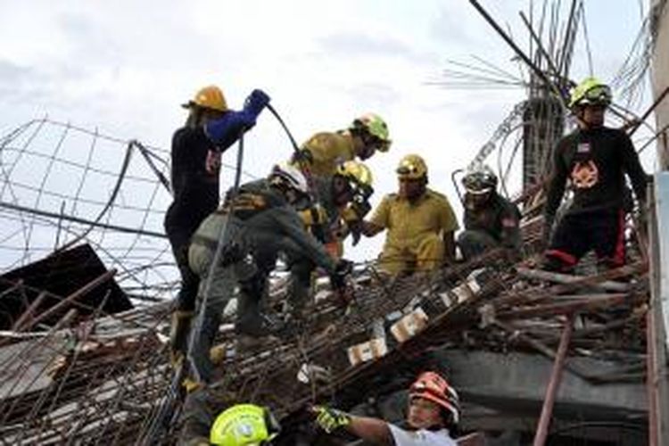 Anggota tim penyelamat bekerja mencari korban runtuhnya sebuah bangunan enam lantai yang tengah dalam proses pembangunan di provinsi Pathum Thani, Thailand, Senin (11/8/2014).