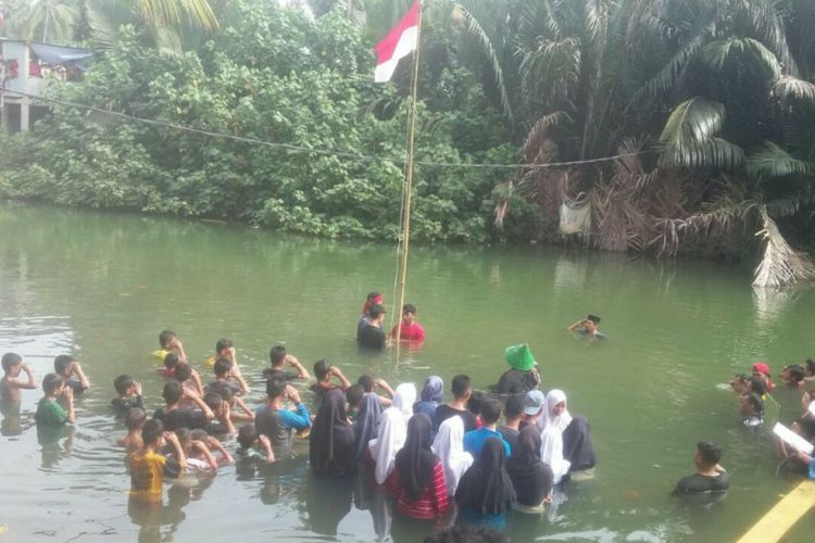 Warga RW 06, Kampung Kaccia, Kelurahan Barombong, Kecamatan Tamalate, Makassar upacara pengibaran bendera merah putih di dalam sungai, Kamis (17/8/2017).