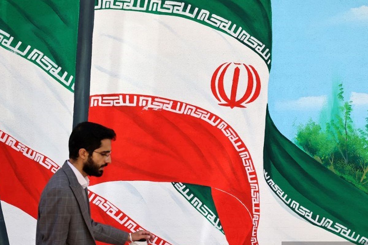 Seorang pria berjalan melewati gambar mural bendera Iran di Teheran, Sabtu (26/10/2024), pada hari ketika serangan Israel ke Iran terjadi.