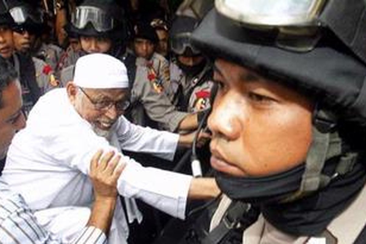 Tersangka terorisme, Abu Bakar Baasyir, dengan kawalan ketat petugas Detasemen Khusus 88 Antiteror usai mengikuti pelimpahan berkas tahap kedua di Kejaksaan Negeri Jakarta Selatan, Senin (13/12/2010). Polisi melimpahkan tersangka ke kejaksaan bersama berkas perkara dan sejumlah barang bukti. Baasyir diduga terlibat sebagai donatur dalam pelatihan militer kelompok teroris di Pegunungan Jalin Jantho, Aceh Besar, Nanggroe Aceh Darussalam. 