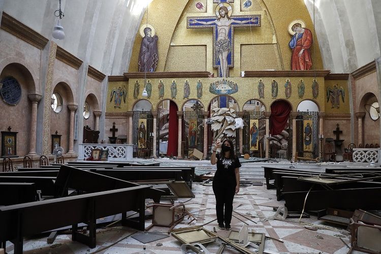 Seorang wanita tampak mengambil foto melalui ponselnya di sebuah gereja yang rusak berat setelah ledakan hebat di Beirut, Lebanon. Rabu, 5 Agustus 2020.
