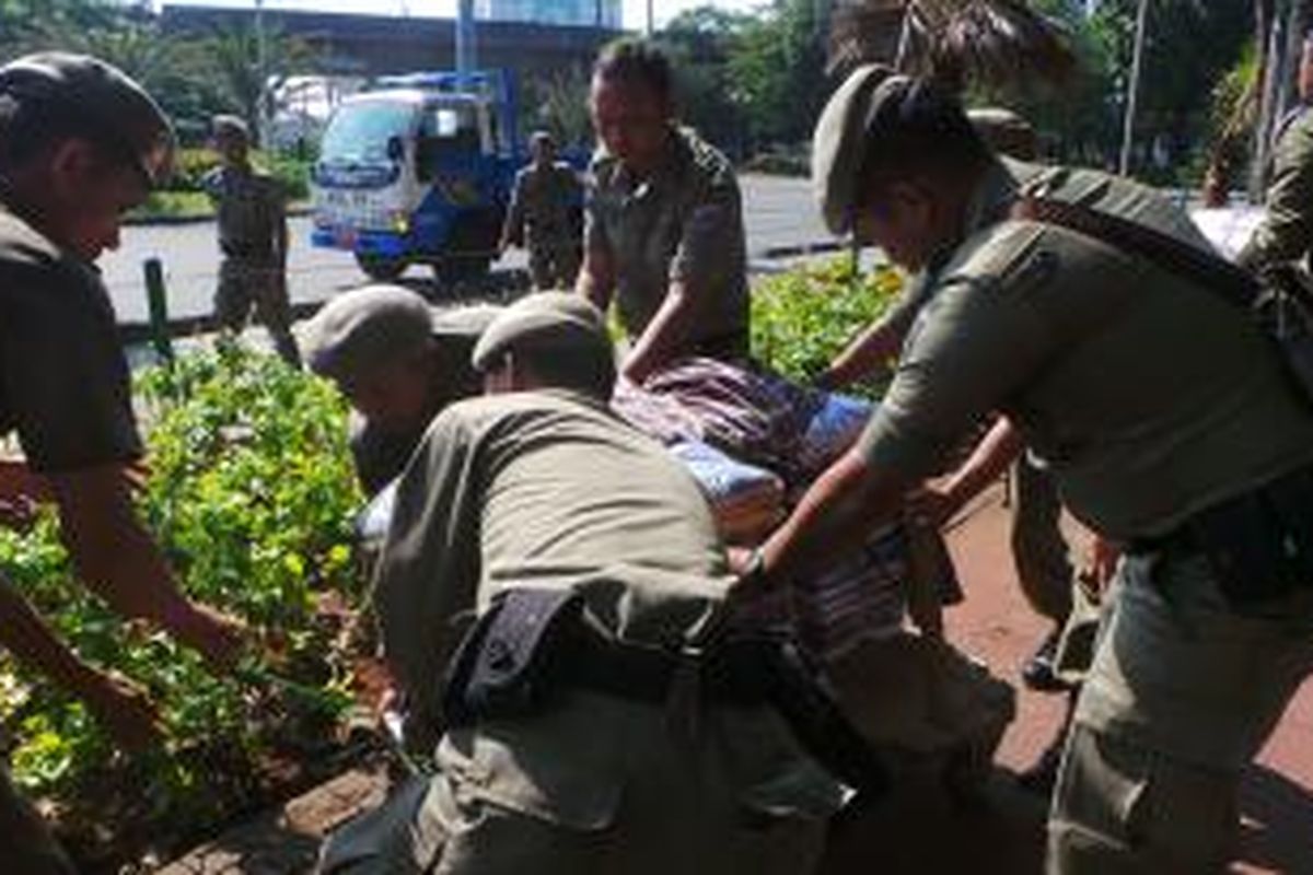 Petugas Satpol PP menyita barang dagangan dari PKL di Monas yang disembunyikan pedagang di semak taman. Sabtu (2/8/2014).