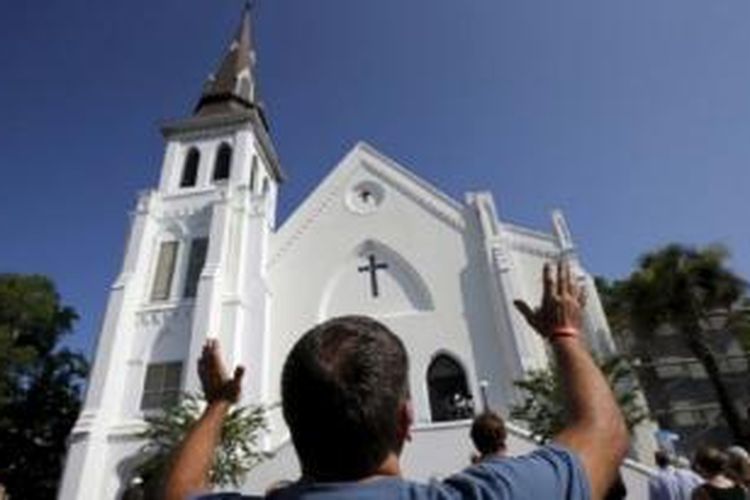 Robin Goolfby, salah seorang jemaat yang tidak bisa masuk akibat penuhnya gereja, mengangkat tangannya di depan gereja Emanuel AME mengikuti kebaktian di Charleston, South Carolina, 21 Juni 2015. 
