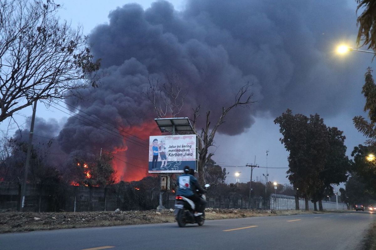 Pengendara melintas di sekitar area tangki T-301 yang terbakar di Pertamina RU VI Balongan, Kabupaten Indramayu, Jawa Barat, Rabu (31/3/2021) sekitar pukul 18.00.

