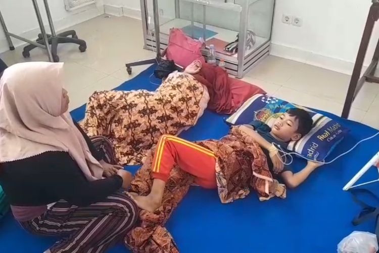 Seorang ibu rumah tangga menunggui anaknya yang diduga keracunan makanan dari MBG di Puskesmas Mantingan, Kecamatan Mantingan, Kabupaten Ngawi, Jawa Timur, Kamis (4/12/2025).